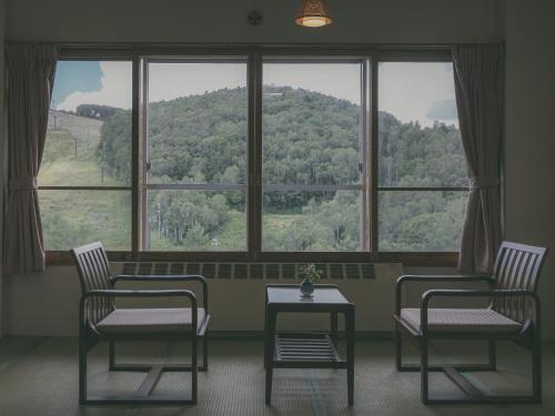 two chairs and a table in front of a large window at Chalet Shiga in Yamanouchi
