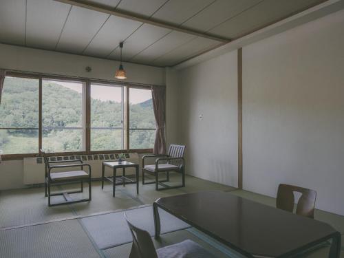 a living room with chairs and a table and windows at Chalet Shiga in Yamanouchi
