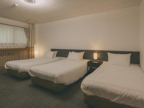 a hotel room with two beds and a window at Chalet Shiga in Yamanouchi