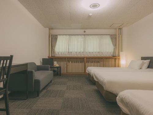 a hotel room with two beds and a couch and a window at Chalet Shiga in Yamanouchi