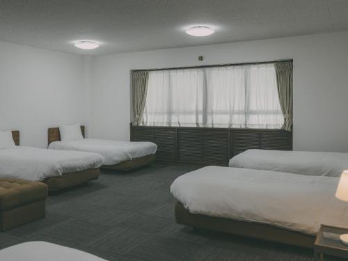 a room with three beds and a window at Chalet Shiga in Yamanouchi