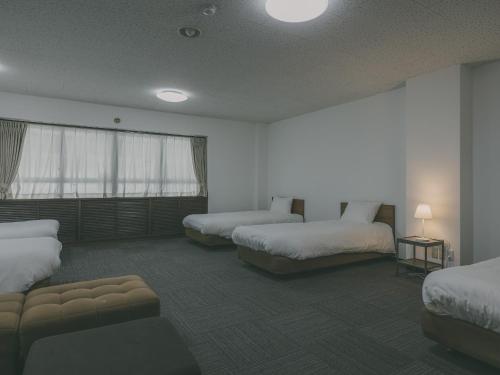 a hotel room with two beds and a couch at Chalet Shiga in Yamanouchi