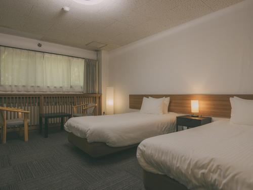 a hotel room with two beds and a window at Chalet Shiga in Yamanouchi