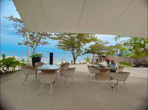 a group of tables and chairs with the beach in the background at Mactan Newtown Beach Condo in Mactan