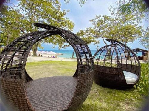 two wicker chairs sitting on the grass near the ocean at Mactan Newtown Beach Condo in Mactan