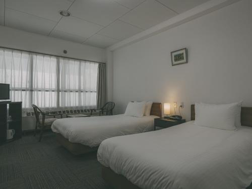 a hotel room with two beds and a window at Chalet Shiga in Yamanouchi