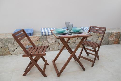 a wooden table and two chairs with bowls and glasses at Areti 1 & Areti 2 in Kilada