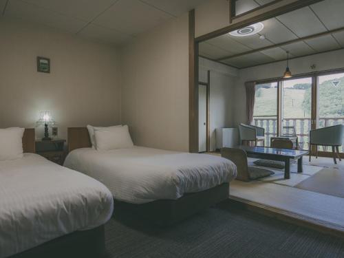a hotel room with two beds and a balcony at Chalet Shiga in Yamanouchi