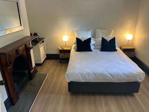 a bedroom with a bed with two lamps and a fireplace at The Rec Hotel Waroona in Waroona