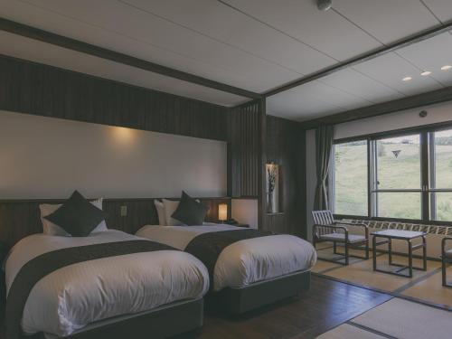 a bedroom with two beds and a table and chairs at Chalet Shiga in Yamanouchi
