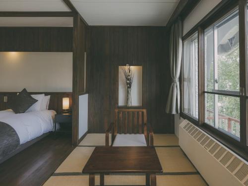 a bedroom with green walls and a bed and a table at Chalet Shiga in Yamanouchi