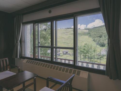 a room with a table and a window with a view at Chalet Shiga in Yamanouchi