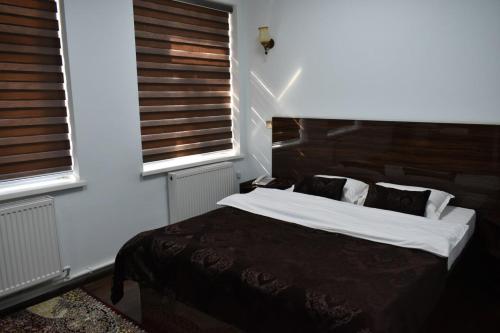 a bedroom with a large bed and two windows at ADMIRAL in Termiz