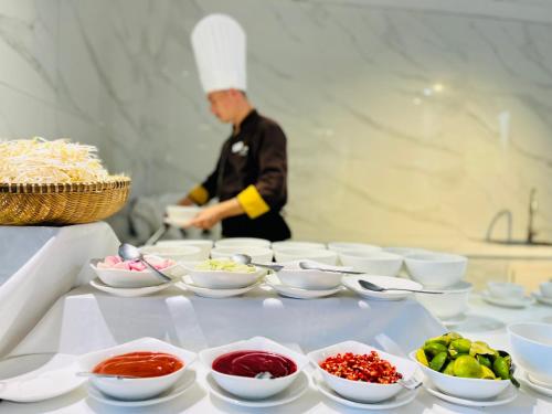 a chef preparing food on a table with bowls of food at Ocean Pearl Hotel Phu Quoc in Phu Quoc