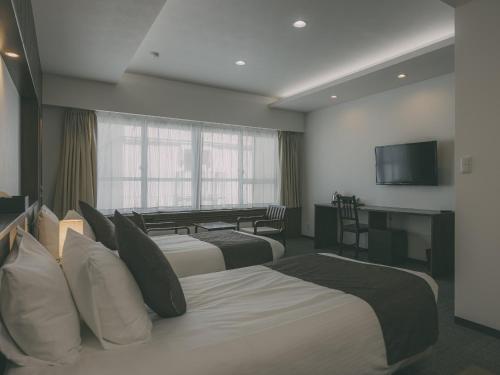 a hotel room with two beds and a television at Chalet Shiga in Yamanouchi