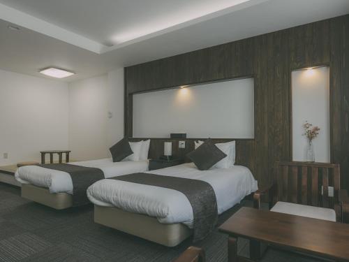 a hotel room with two beds and a large screen at Chalet Shiga in Yamanouchi