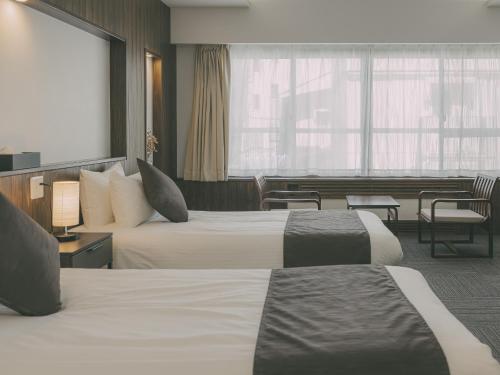 a hotel room with two beds and a living room at Chalet Shiga in Yamanouchi