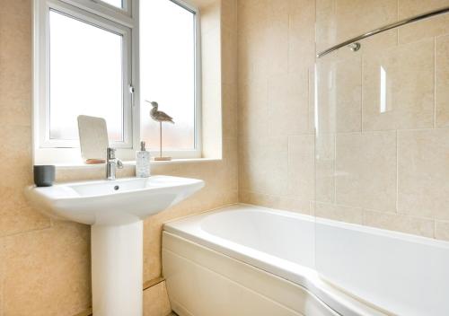a white bathroom with a sink and a bath tub at Hillview in Llanbedrog