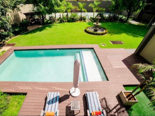 a swimming pool in a yard with two chairs at One O Eight Boutique Hotel in Benoni