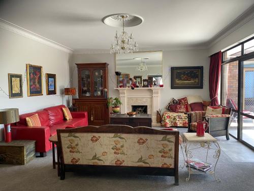 a living room with red furniture and a chandelier at Gracious on the Grove in Kerikeri