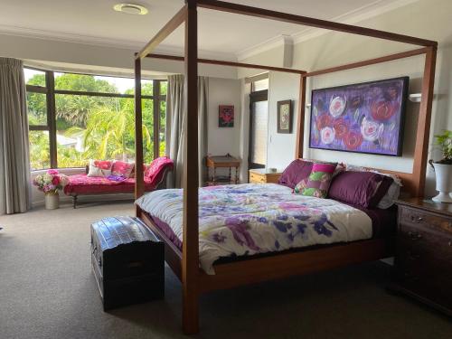a bedroom with a canopy bed and a window at Gracious on the Grove in Kerikeri