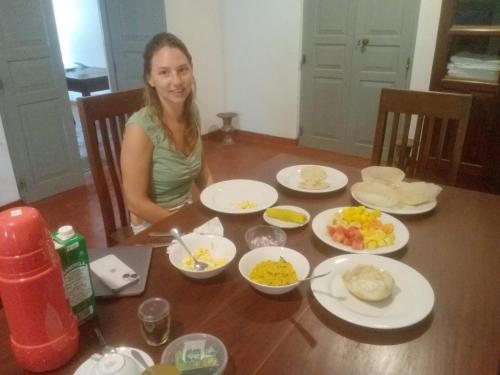 una mujer sentada en una mesa con platos de comida en Villa 95 Hiriketiya, en Dikwella