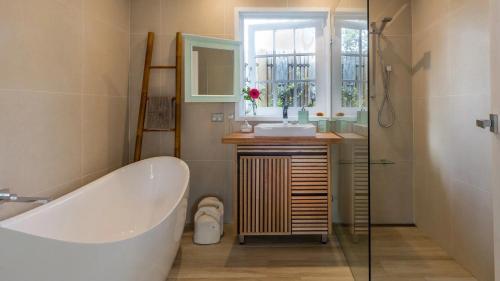 a bathroom with a tub and a sink and a mirror at Beachfront- The Art Cottage- Pet Friendly in Vincentia