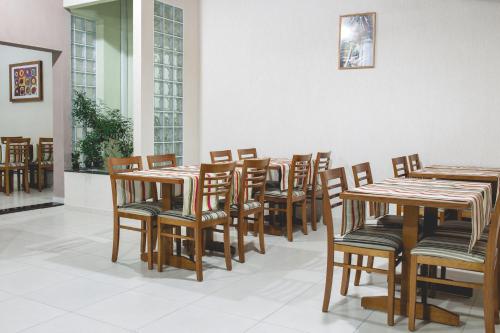 - une rangée de tables et de chaises en bois dans une chambre dans l'établissement Pousada Santa Inês, à Cachoeira Paulista