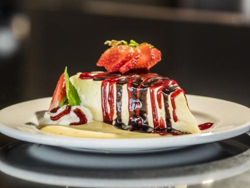 a dessert on a white plate with strawberries and syrup at Rodd Miramichi in Miramichi