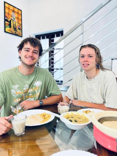 two people sitting at a table with plates of food at Riverrootsstays in Munroe Island