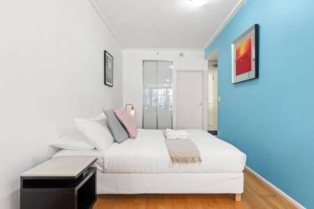 a bedroom with a white bed and a blue wall at A Comfy Studio for 5 Next to Darling Harbour in Sydney