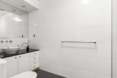 a white bathroom with a toilet and a sink at A Comfy Studio for 5 Next to Darling Harbour in Sydney