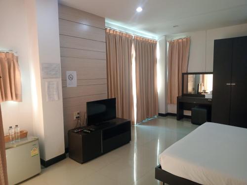 1 dormitorio con 1 cama, TV y escritorio en โรงแรมสบายเพลส (หินสองก้อน) en Lop Buri
