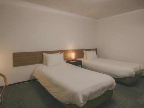 a hotel room with two beds and a lamp at Chalet Shiga in Yamanouchi