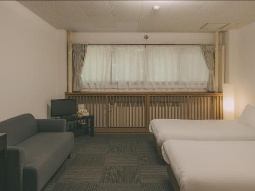 a room with two beds and a couch and a window at Chalet Shiga in Yamanouchi