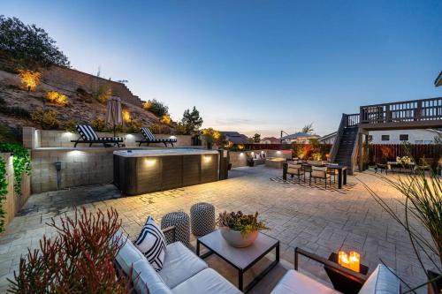 een patio met witte banken, tafels en stoelen bij Luxury Getaway: Hot Tub,Pool Table,Fire Pit in Palmdale