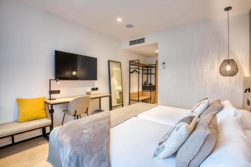 Un dormitorio con una cama, un escritorio y un televisor. en Hotel Costabella, en Girona
