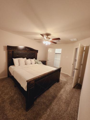 a bedroom with a large bed with a ceiling fan at Shella Home in Missouri City