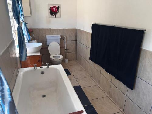a bathroom with a tub and a toilet and a sink at The Calvert in Fort Beaufort