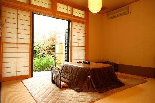 a room with a table and a large window at Ryokan Kutsuroginoya Yuu in Takayama
