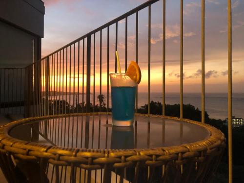 a drink on a table on a balcony with an orange slice at 恩納オーシャンビュースイート in Nakadomari