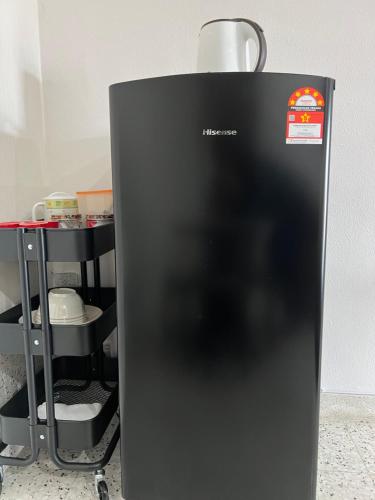 a black refrigerator sitting next to a shelf at Naura Roomstay in Sungai Petani