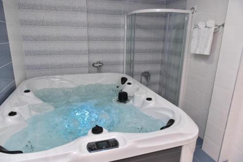 a white bath tub with blue water in a bathroom at Style Rooms in Skopje