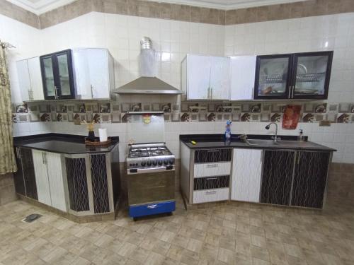 eine Küche mit weißen Schränken und einem Herd mit Backofen in der Unterkunft شقة المعبيلة الجنوبية in Ghursheba