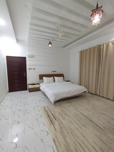 een slaapkamer met een groot wit bed en een kroonluchter bij شقة المعبيلة الجنوبية in Ghursheba