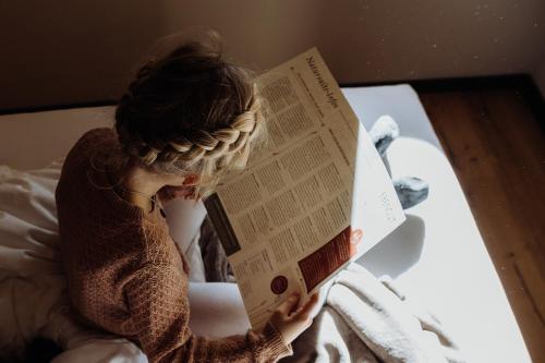 a woman laying in bed reading a book at Biohof Ebengut in Maria Alm am Steinernen Meer
