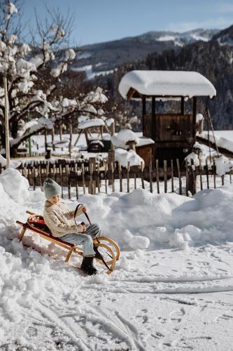 a boy sitting on a sled in the snow at Biohof Ebengut in Maria Alm am Steinernen Meer