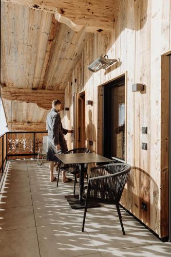 a woman walking in a room with a table and chairs at Biohof Ebengut in Maria Alm am Steinernen Meer