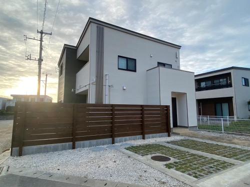 una casa bianca con una recinzione di legno di fronte di Rs Stay Villa MIYAKO B a Miyakojima