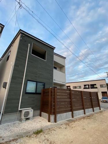 una casa con una recinzione di legno di fronte ad essa di Rs Stay Villa MIYAKO B a Miyakojima